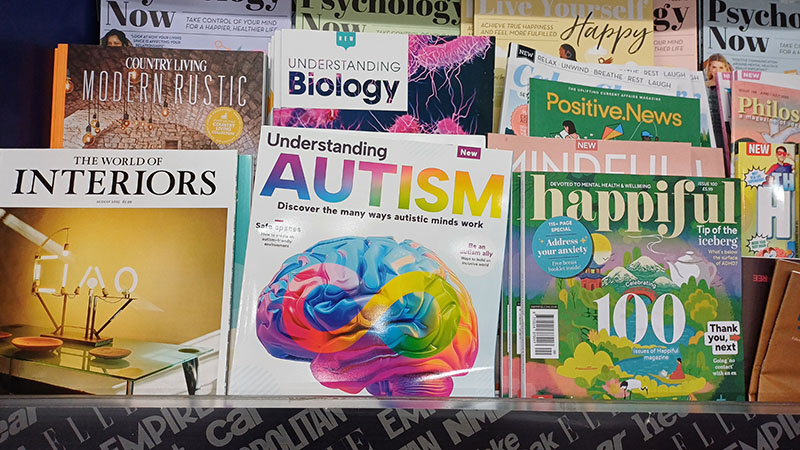 A photograph of 'Understanding Autism' magazine on a rack with other magazines in a newsagent